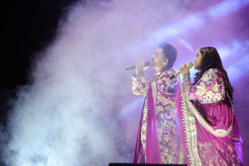 Vocalists performing together under stage lights